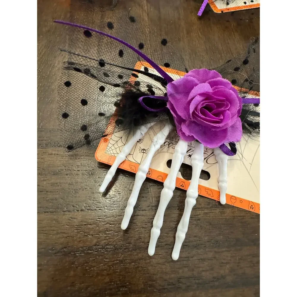 Purple rose hair clip with black netting and purple ribbon on a skeleton hand